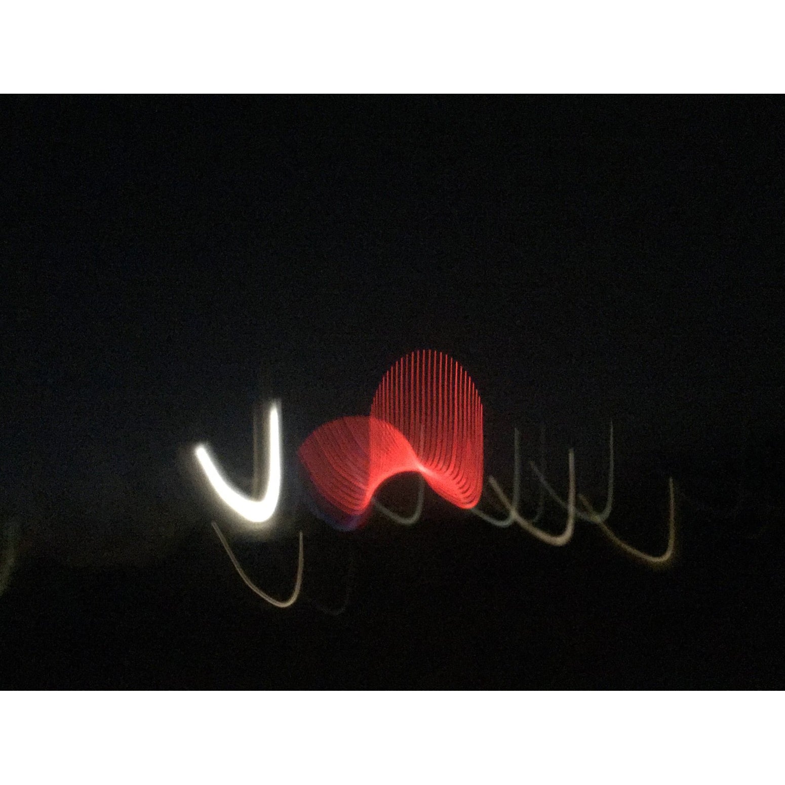 Abstract light art with red and white shapes on a black background. Chromatic reference image evoking the shifting lavender blue and crimson tones of tanzanite
