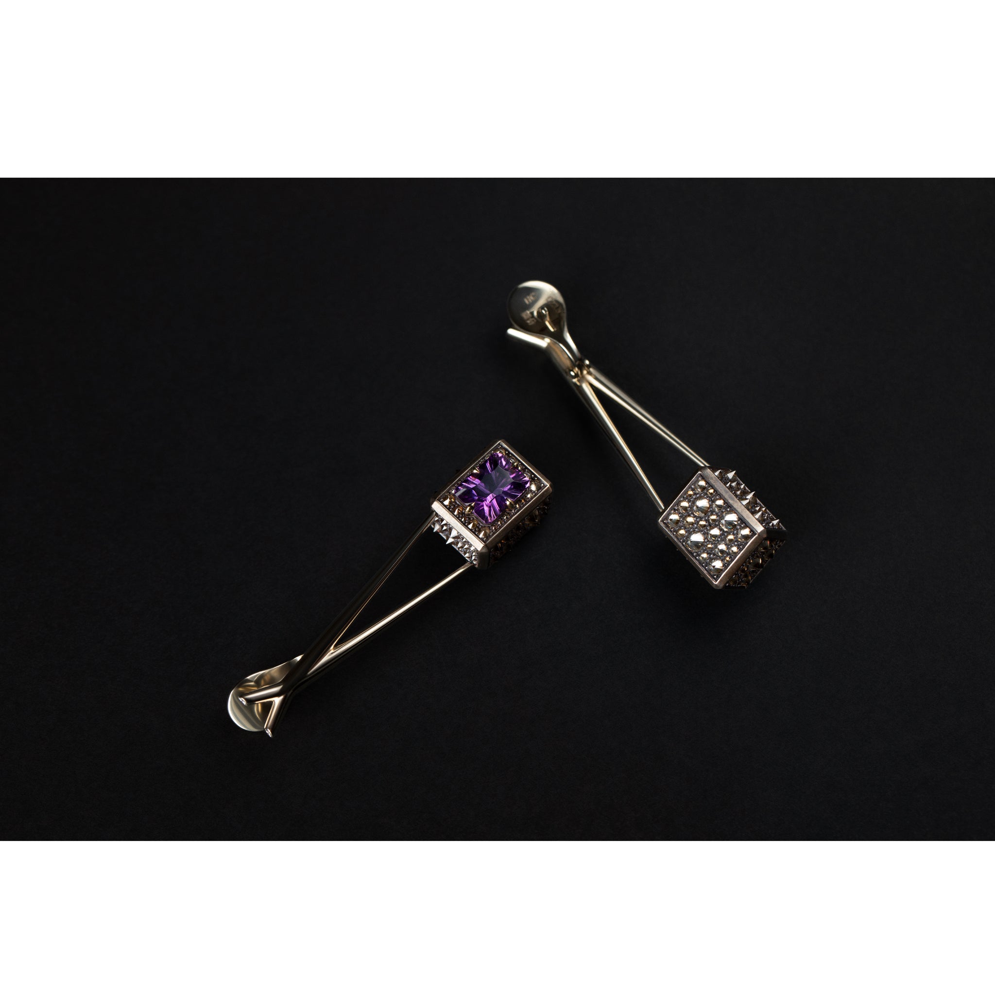 Angled view of the Atlas Spur Earrings showing elongated gold structure and violet amethyst stones

