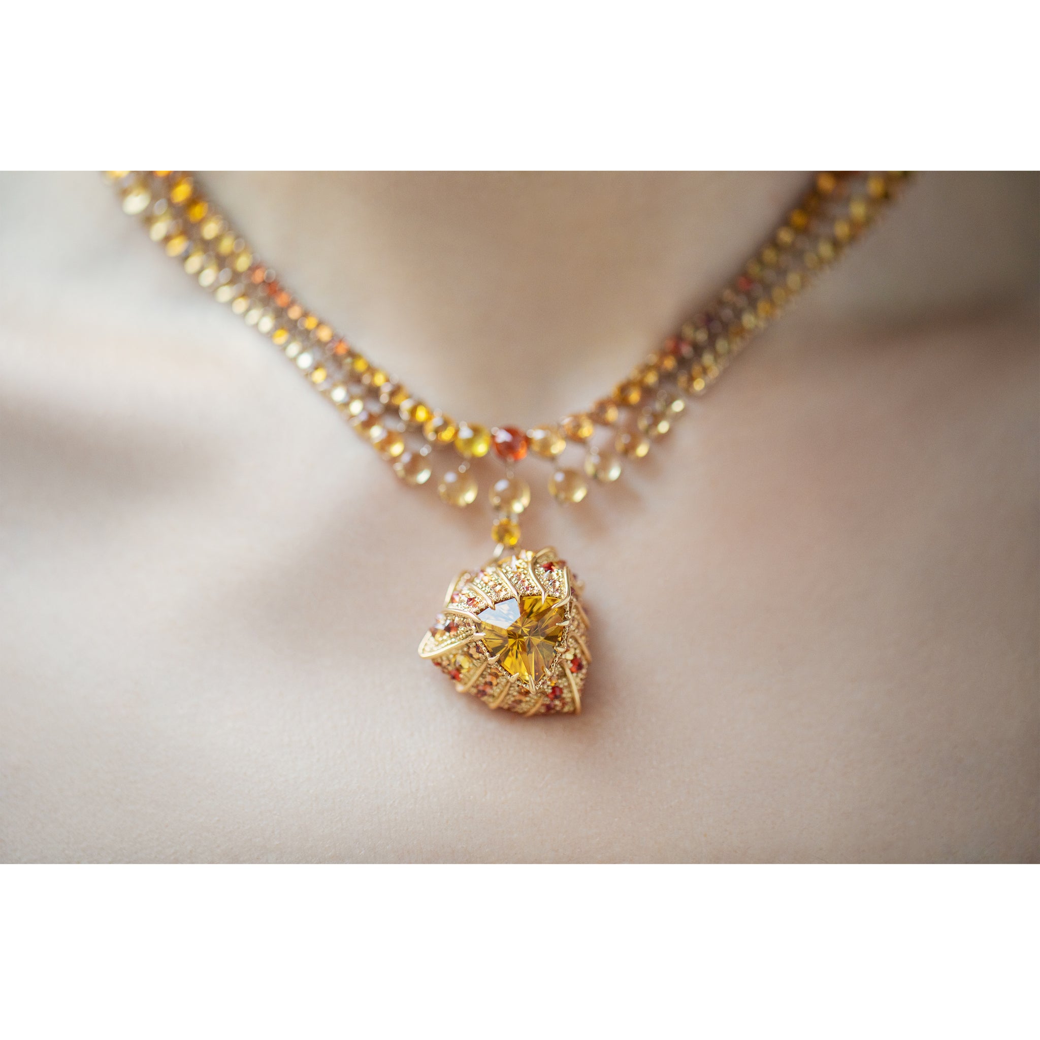 Detail view of the Stereón Aurion Necklace, highlightinga  graduated orange sapphire chain and pendant
