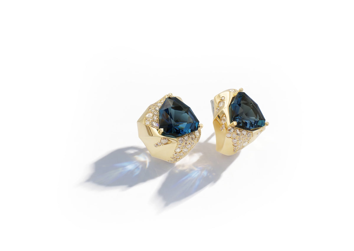 Phokialí Earrings shown at an angle, the trillion-cut London blue topaz set within sculptural gold volumes.