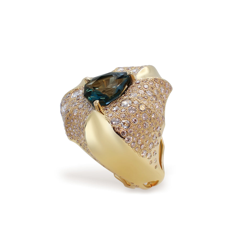 A gold ring with a large blue topaz at the center and intricate pavé arrangement of brilliants and rose-cut  Phokialí Ring by Hugo Cahill, sculptural gold ring with diamond snowflake pavé
diamonds around it.